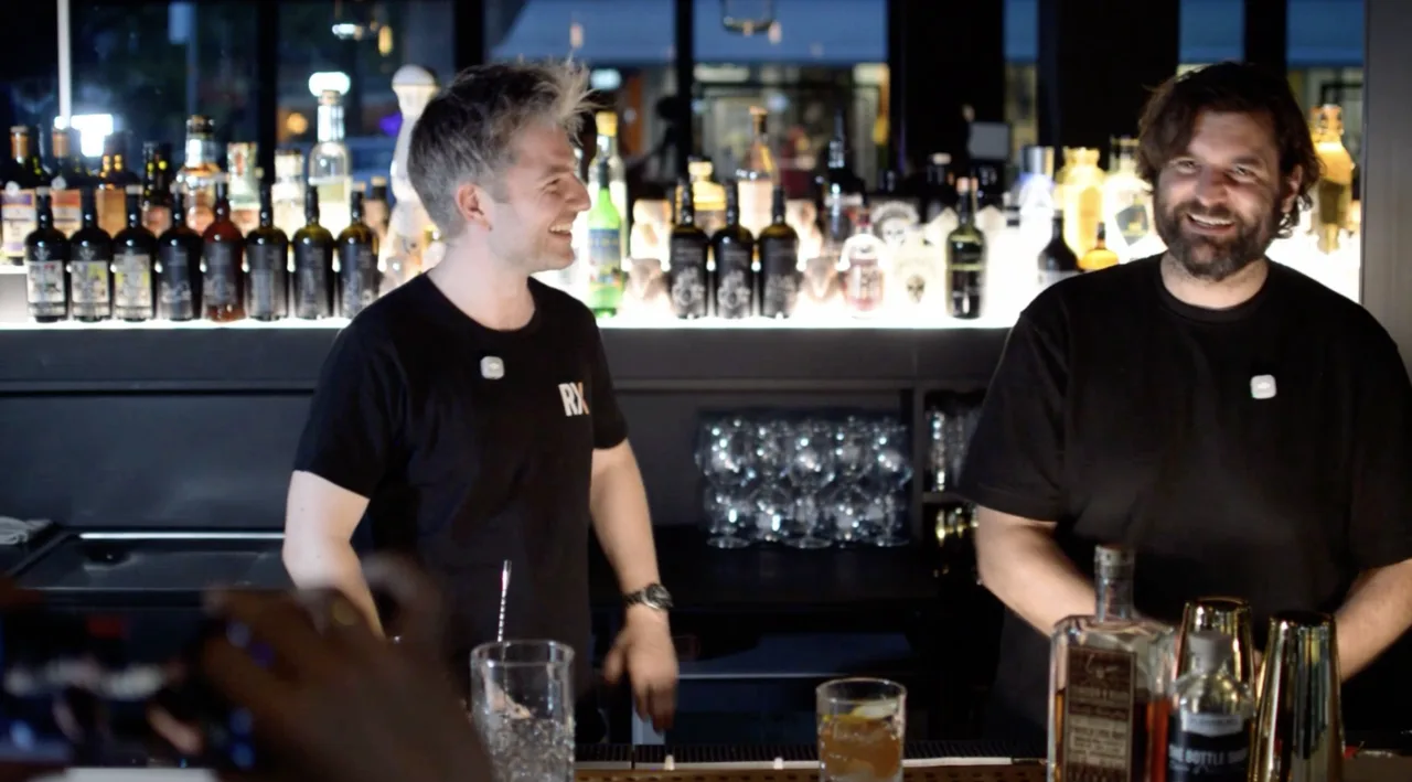 Oliver und Stefan Glück lachen hinter dem Bartresen im Ludwig, vorn ein fertiger Rum Old Fashioned mit Orangenzeste