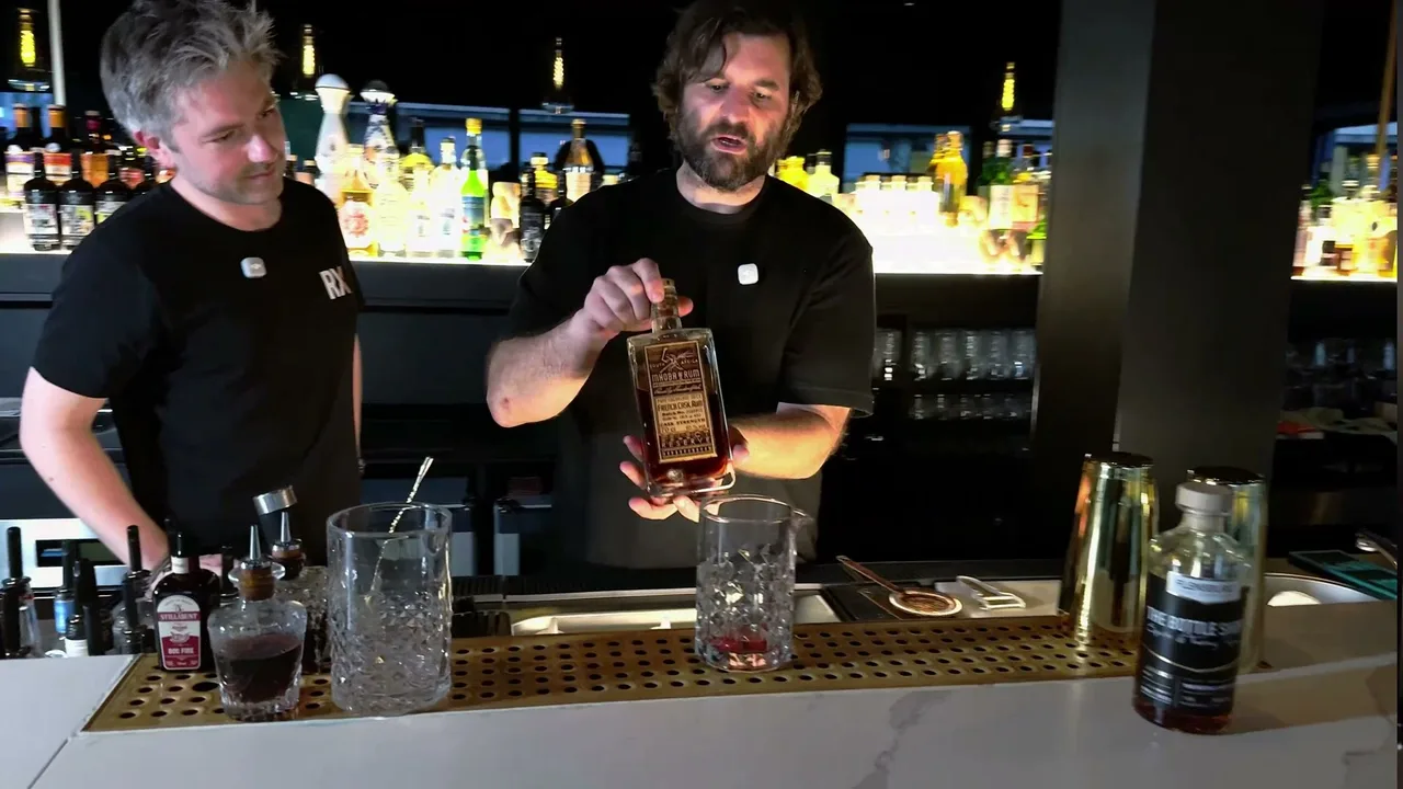 Stefan Glück präsentiert die Flasche Mhoba Select Reserve French Cask, davor das Rührglas mit gemuddeltem Chili, daneben Doc-Fire-Bitters und die Bottle-Shop-Flasche