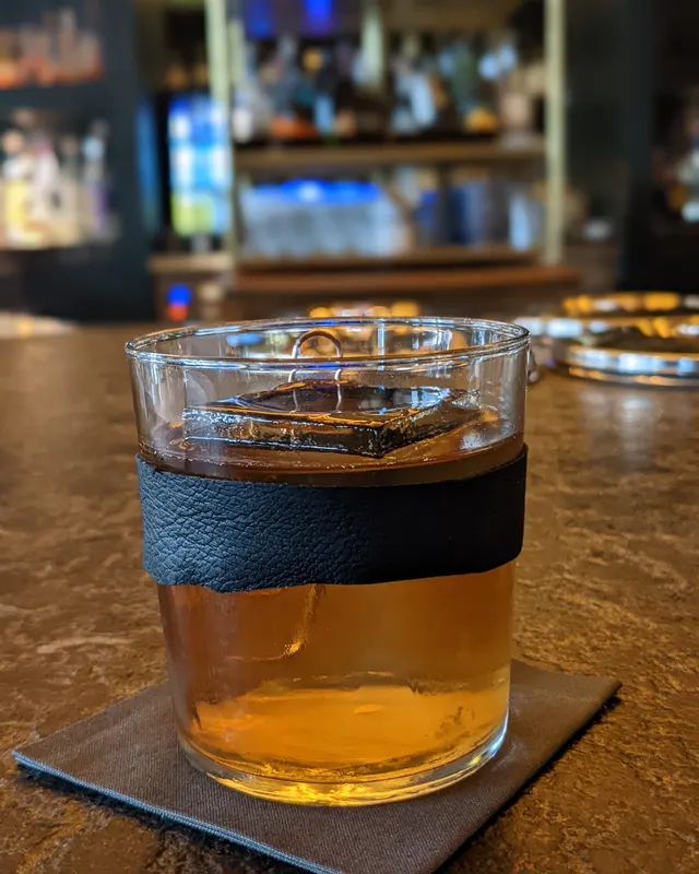 Old Fashioned in einem Glas mit Ledermanschette auf schwarzer Serviette