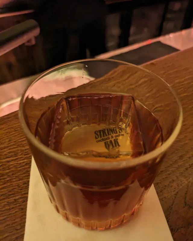Old Fashioned im Rillenglas mit gebrandetem Eiswürfel