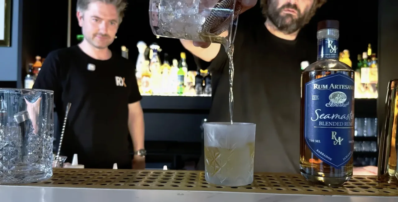 Stefan Glück seiht den Seamaster Old Fashioned in einen gefrosteten Tumbler ab, daneben die Flasche Burke's Seamaster von Rum Artesanal